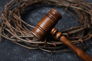 Crown of thorns and judge's gavel on dark textured background, closeup
