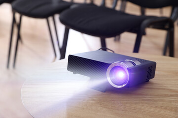 Naklejka premium Modern video projector on wooden table indoors. Displaying image