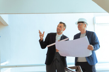 Architect and engineer reviewing blueprints at construction site