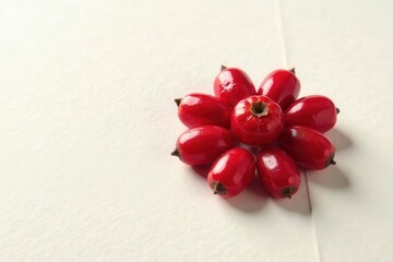 A vibrant cluster of glossy red berries arranged in a captivating floral pattern, showcasing their rich color and smooth texture against a subtly textured off-white backdrop.