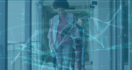 Tech team walking corridor, front woman scrolling phone then tapping tablet visualizing DNA helix - Powered by Adobe