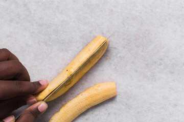 Overhead view of plantains being sliced on a white countertop, top view of plantains being cut on white background