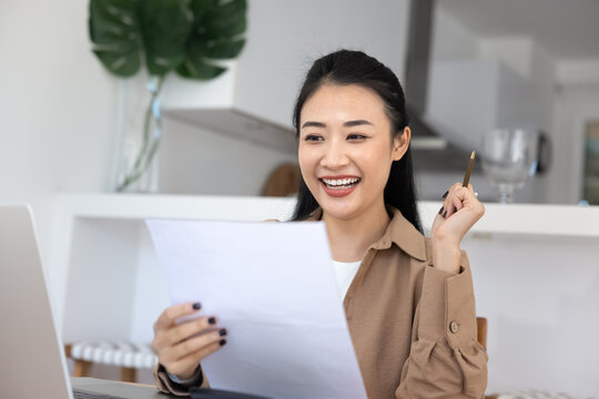Young Asian woman reading letter or document with happy personal news, get job offer, received acceptance letter for course or university admission, celebrate fantastic offer with joyful expression