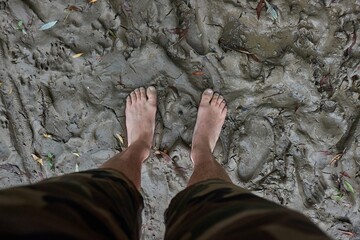 Barefoot man standing in the mud