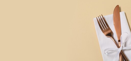 Napkin and cutlery on beige background with space for text, closeup
