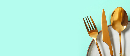Beautiful table setting with golden cutlery on turquoise background