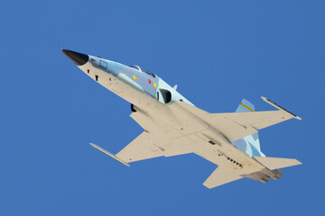 bottom view  of a F-5E Tiger II in the aggressor color scheme, approaching in beautiful light