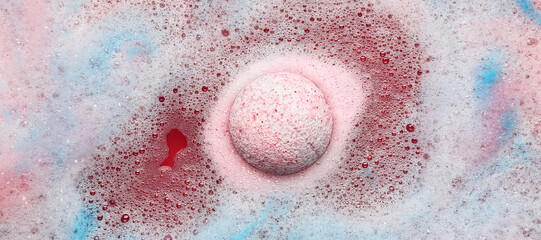 Pink bath bomb dissolving in blue water