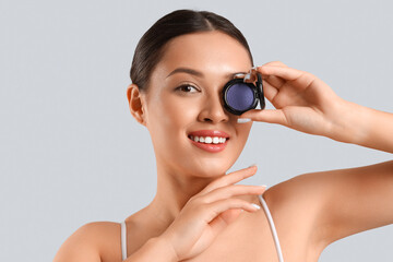 Young Asian woman with mono eyeshadows on light background, closeup