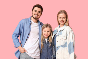 Fototapeta premium Happy young family with daughter smiling together, parents and child posing on pink background, family bonding and childhood