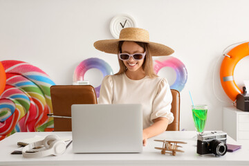 Young businesswoman with laptop waiting for summer vacation in office