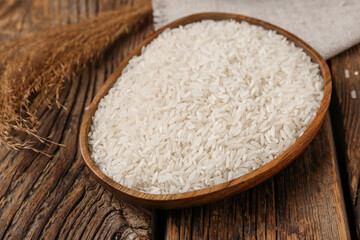 Plate with raw rice on wooden background