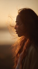 Golden Hour Portrait Woman with Windblown Hair at Sunset. A serene image capturing the beauty of a young woman in the warm glow of the setting sun.
