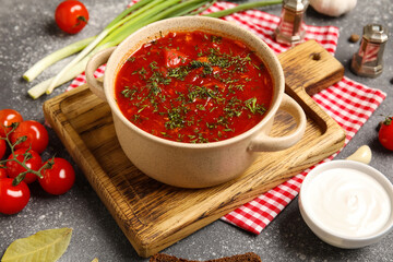 Bowl of tasty Ukrainian borscht and ingredients on dark background, closeup