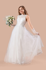 Beautiful bride in white wedding dress with flowers on beige background