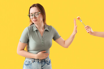 Young woman rejecting hand with honey on yellow background. Food Allergy Awareness Month