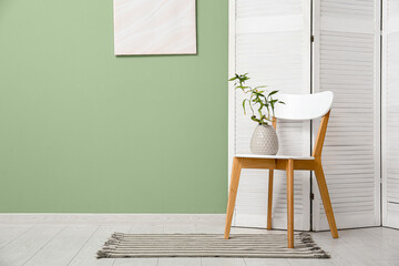 Vase with bamboo stems on chair in stylish room