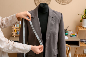 Obraz premium Female tailor taking measurements of jacket on mannequin in atelier