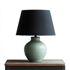 Minimalist ceramic table lamp with a speckled light green base and a simple dark gray fabric lampshade sitting on a wooden surface in front of a white background