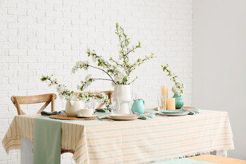 Elegant table setting with plates, glasses and blooming tree branches