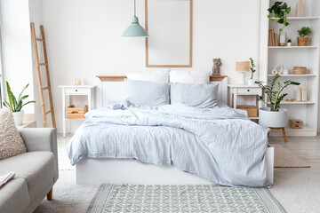 Interior of light bedroom with cozy bed, shelving unit and houseplants