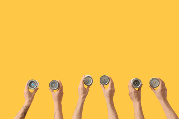 Male hands with paint cans on yellow background