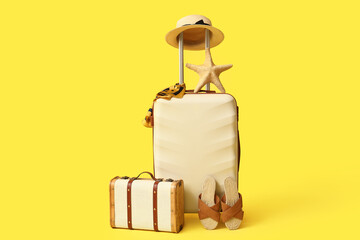 Stylish suitcases, beach accessories and starfish on yellow background