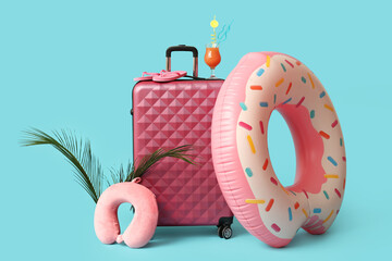 Suitcase with glass of cocktail, beach accessories and palm leaves on color background