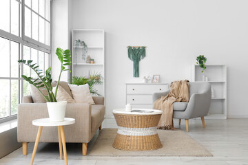 Interior of living room with soft couch, armchair and rattan table