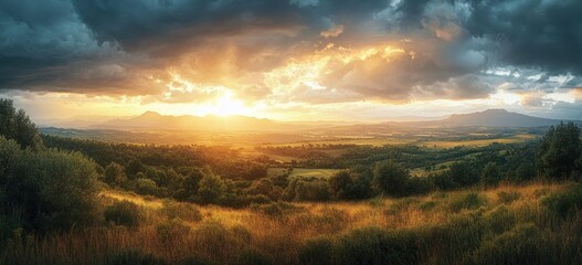 Sunset over a vast landscape with rolling hills, dense forest, golden grassy fields, and dramatic cloudy sky, evoking a peaceful and majestic atmosphere