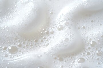 Close-up of soft white foam bubbles with various sizes floating on a smooth surface creating a light and airy texture