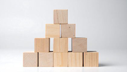 Obraz premium A pyramid of plain wooden blocks is stacked on a white surface against a white background.