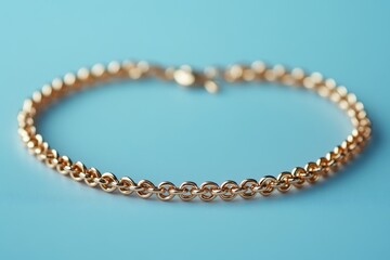 Delicate gold chain bracelet with a lobster claw clasp on a light blue background. Great for jewelry ads, fashion blogs, or gift-giving concepts.