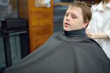 Portrait of a teenager with Down syndrome in a barbershop