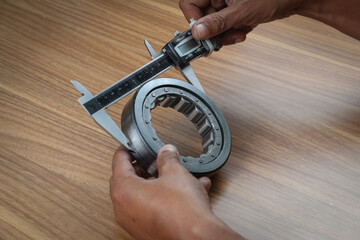 Worker is measuring outside diameter of bearing with a digital vernier caliper micrometer....
