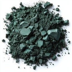 Close-up view of dark green crushed powder pigment scattered on white surface with varied chunks and fine particles creating textured organic pattern