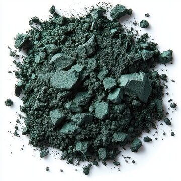 Close-up view of dark green crushed powder pigment scattered on white surface with varied chunks and fine particles creating textured organic pattern