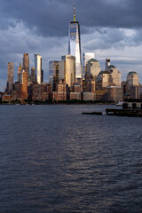 Fototapeta premium New York city. NYC cityscape. Lower Manhattan and One World Trade Center in New York Cit. Skyscrapers of Manhattan located near rippling water of New York bay against blue sky. New York skyscrapers.
