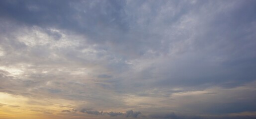 The slightly cloudy afternoon sky with black clouds highlighted by the yellow afternoon sunlight looks beautiful and dramatic.