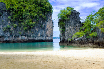 Obraz premium Stunning tropical beach on Hong Island in Krabi Province, Thailand. Surrounded by emerald waters, dramatic limestone cliffs, Ideal for tropical beach pictures, beach screensavers