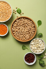Beans in bowls on green background, top view