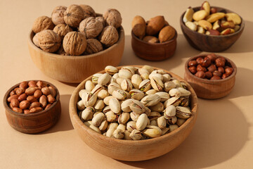 Various nuts in wooden bowls on a beige background