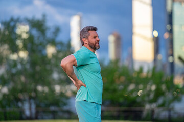 Pain in back after sport. Man with spine injury. Hurt while jogging outdoors. Muscle pain after...