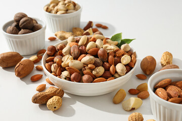 Various nuts in white bowls on a white background