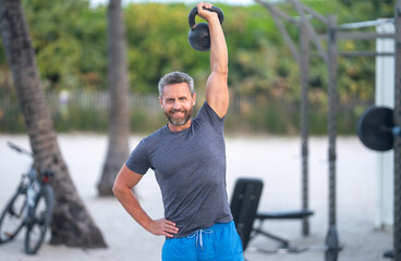 Kettlebell workout outdoors. Athletic man lifting kettlebell. Fit guy training with kettlebell. Shirtless sportsman performing kettlebell exercises. mature man training outdoor. Training in open air.