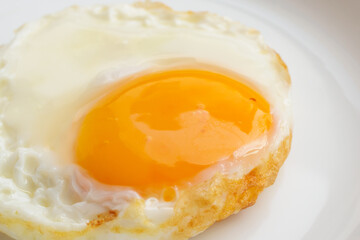 Fried egg on white dish close up