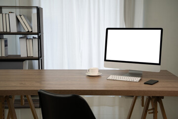 Contact us modern office desk with computer, coffee cup, and smartphone in bright room with bookshelf and curtains in background