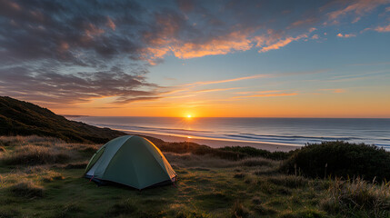 Tent is set up near beach during stunning spring sunset, with vibrant colors in sky and serene ocean view
