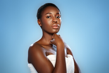 Model poses confidently against a solid blue background, showcasing natural beauty and elegance...