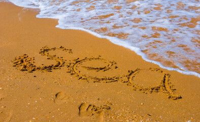 closeup sandy sea beach with sea sign on the sand, summer  sea vacation background